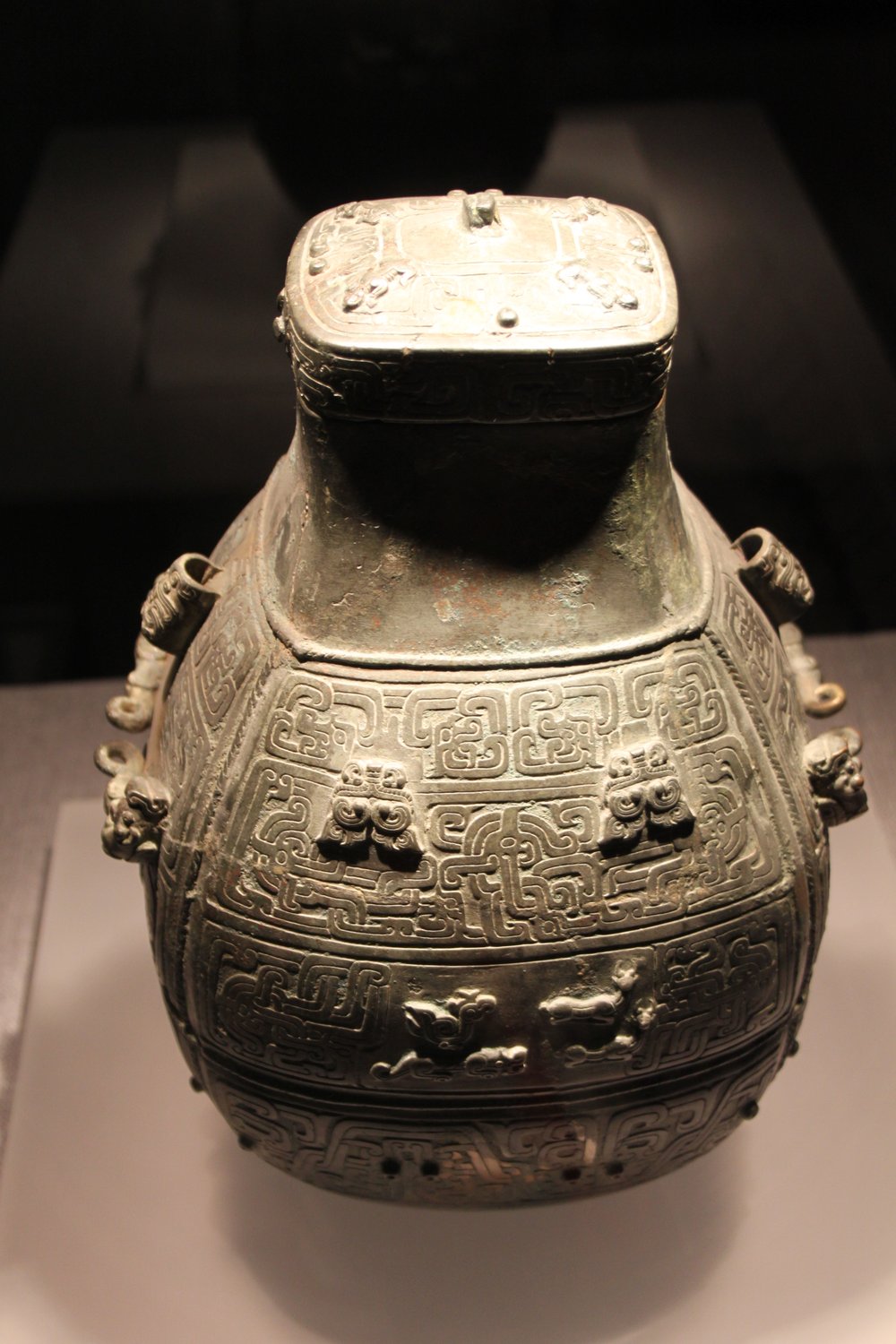 戦国時代の青銅の壺。四角い口と、ふたがある。表面には、細かい渦の模様と、獣の飾りが並んでいる。河南省博物院の展示で、今回見つかった壺ではない。