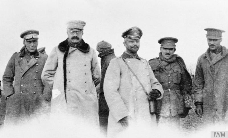 1914年のクリスマス、無人地帯に出て並ぶイギリスとドイツの将校たち。厚いコートと軍帽の男たちが、カメラの方を向いている。白黒写真。